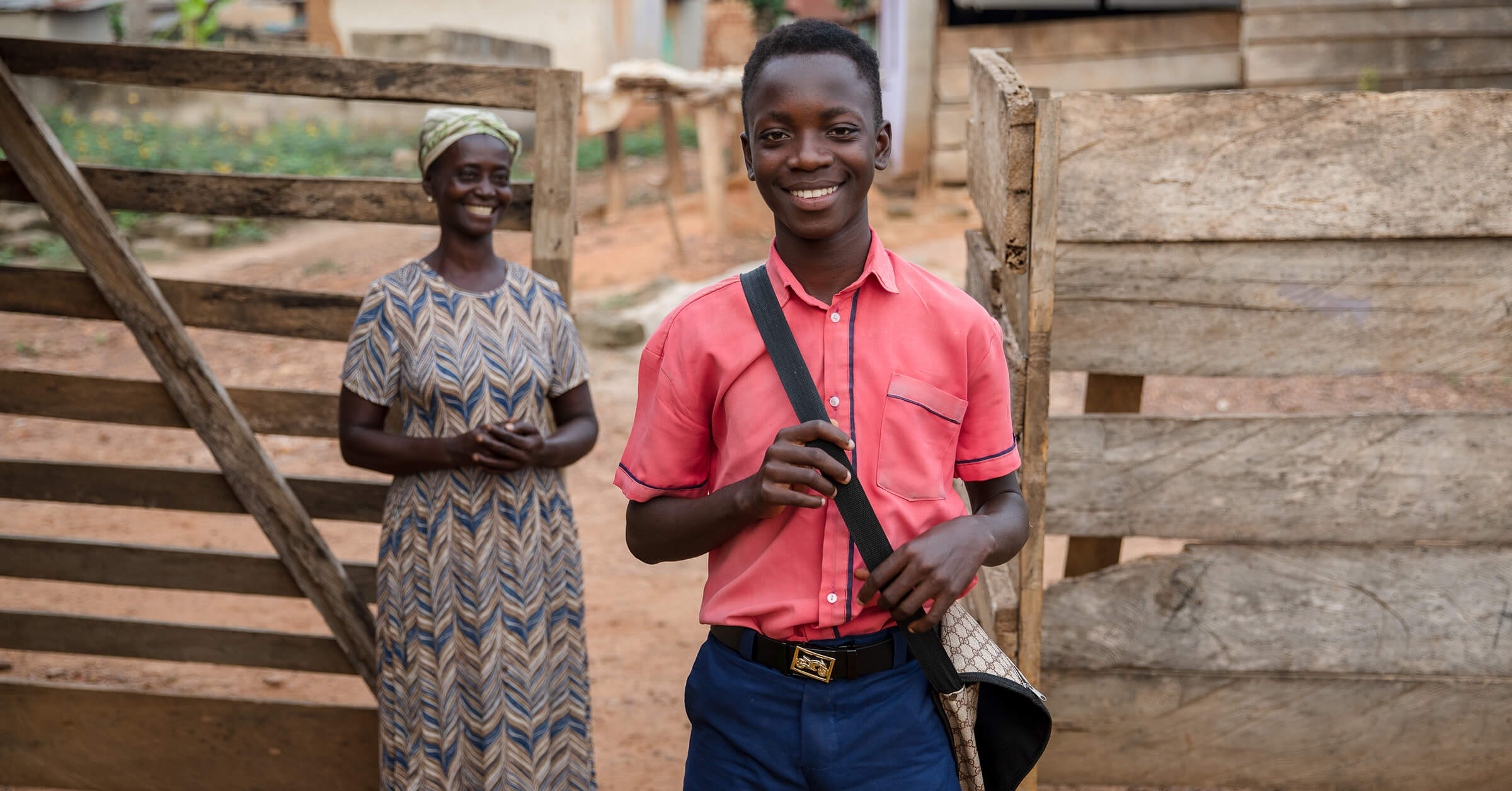 Reilun kaupan viljelijäperhe Ghanassa: vasemmalla nainen hymyilee ja keskellä poika hymyilee koululaukun kanssa. 